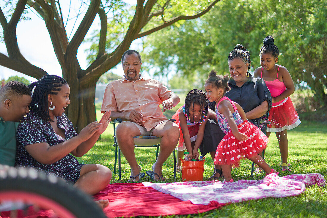 Multigenerational family splashing water in park