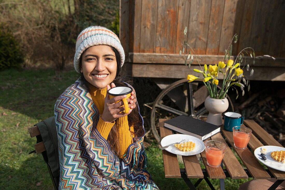 Happy young woman enjoying breakfast at campsite