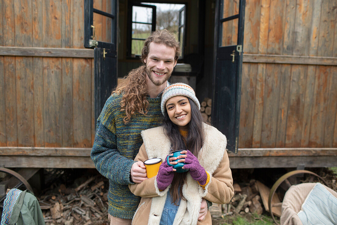Happy young couple drinking coffee outside tiny cabin rental
