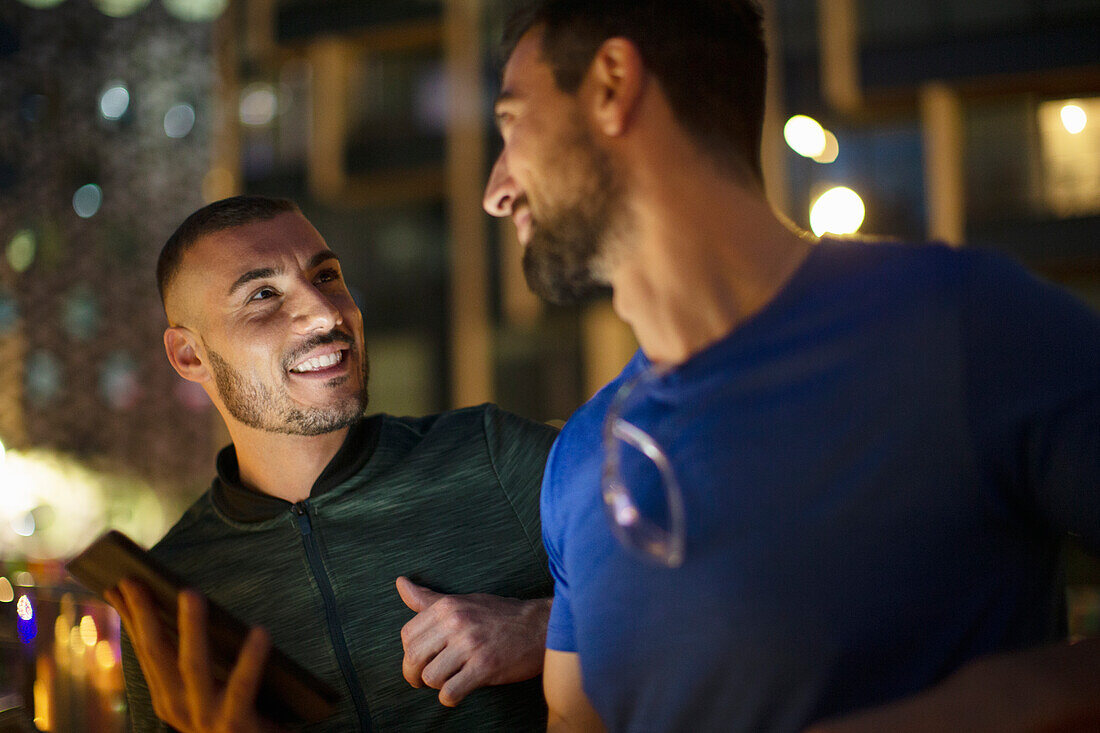 Happy male friends talking at night