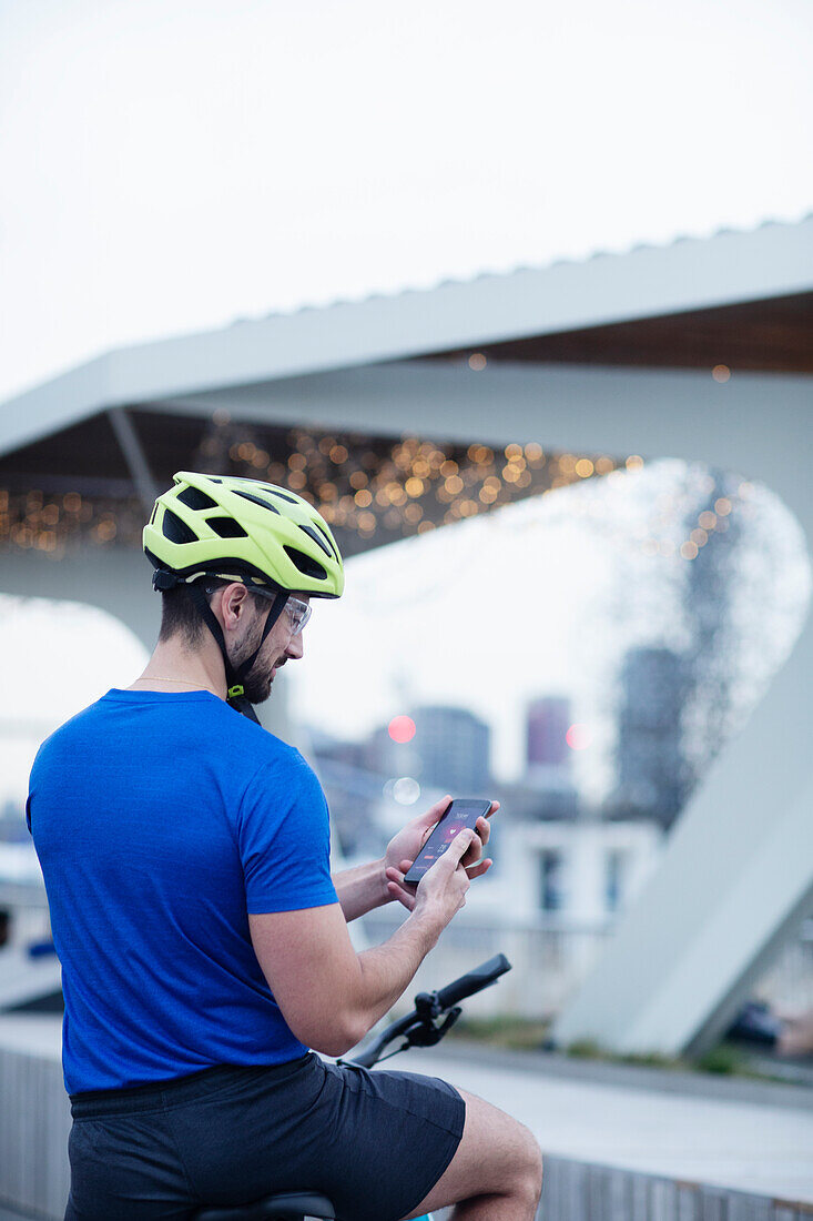 Man on bicycle using smartphone in city