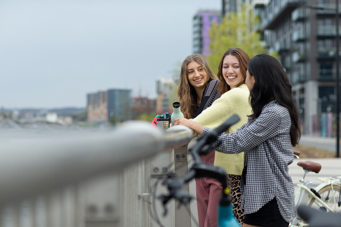Happy young female friends at urban railing