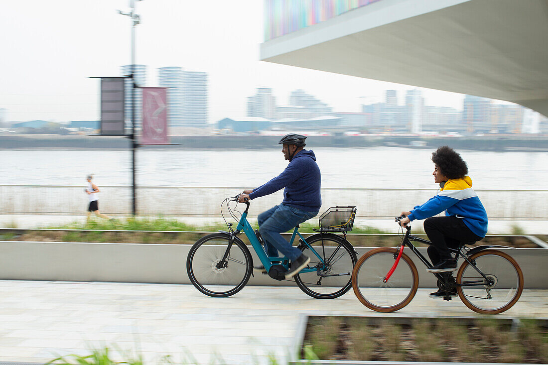 Father and son riding bicycles along urban waterfront