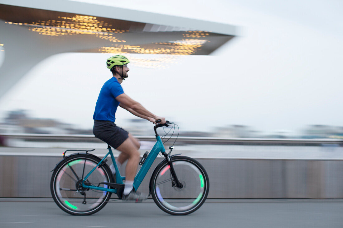 Man riding illuminated bicycle in city