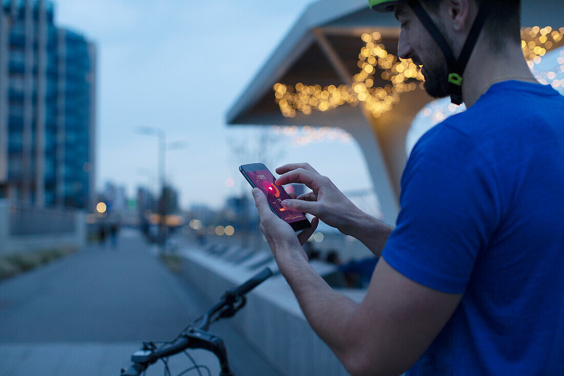Man on bicycle looking at heart rate on smartphone app