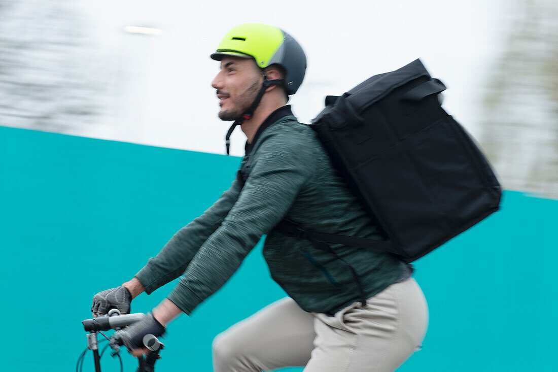 Male delivery man riding bicycle with bag