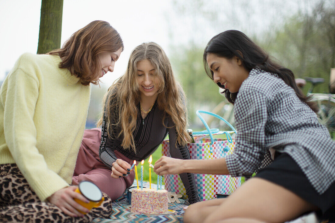 Young female friends celebrating birthday with cake in park