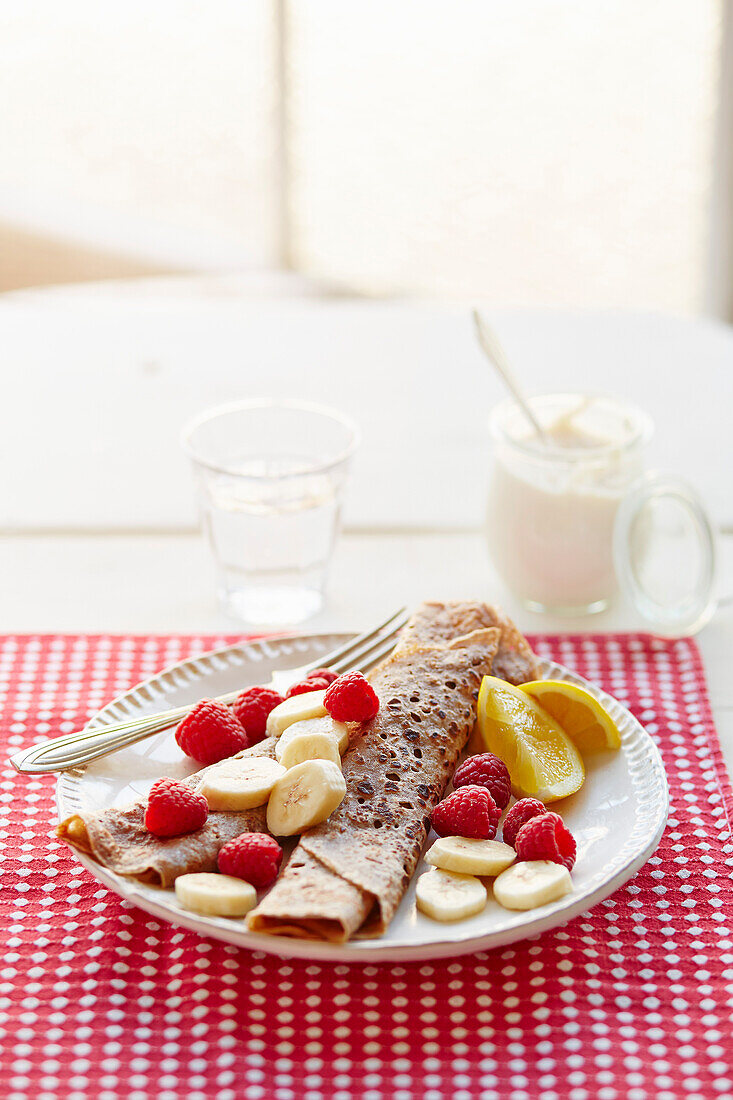 Cinnamon crêpes with nut butter, sliced banana and raspberries