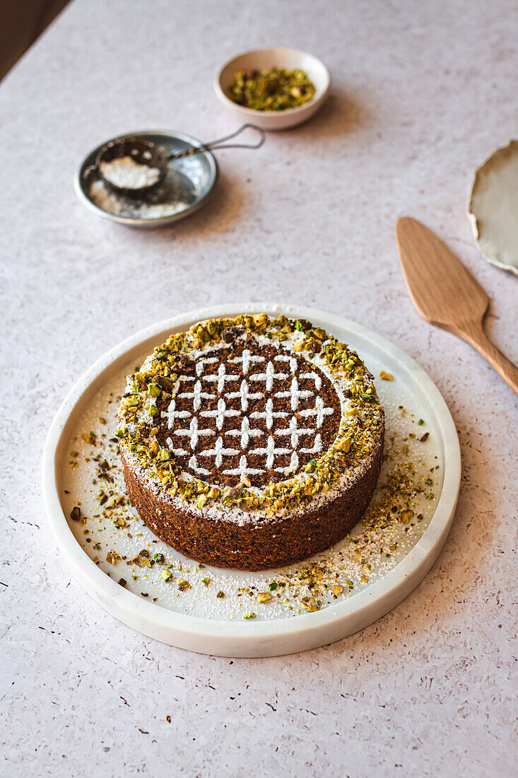 Gluten free pistachio and almond cake with patterned icing sugar decoration