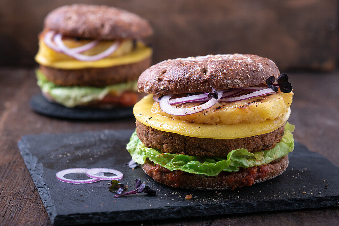 Vegan burgers with bean patty, cheese substitute and grilled pineapple