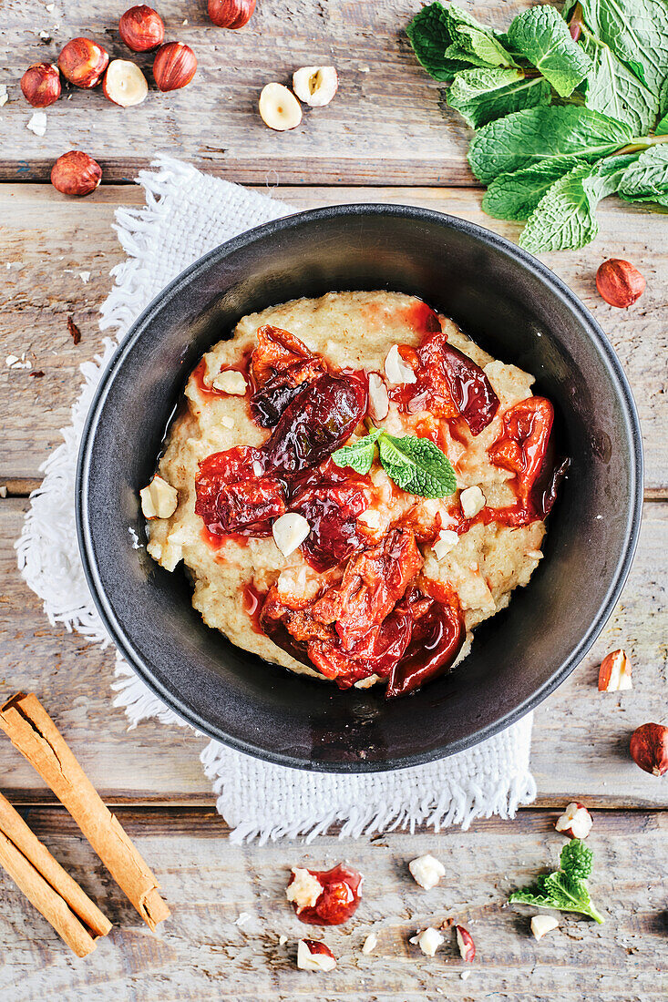 Vegan spelt semolina porridge with cinnamon, plum compote and nuts