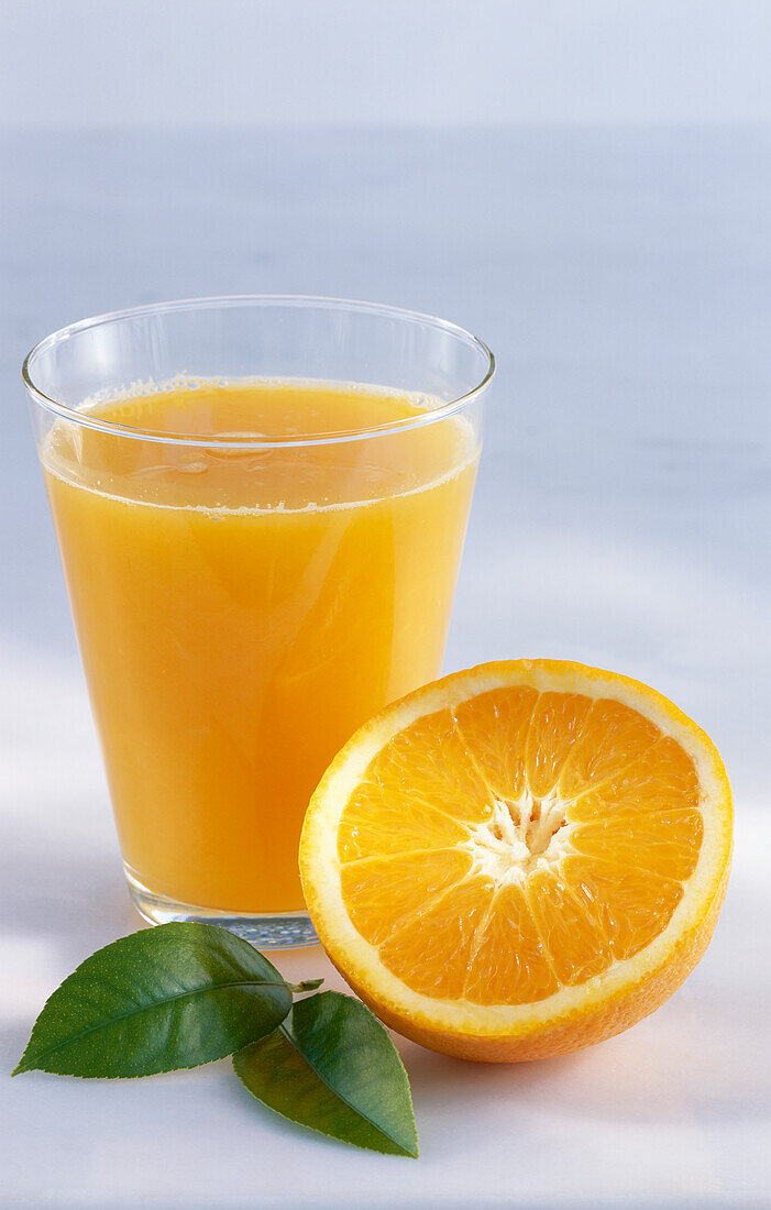 A glass of orange juice and half an orange
