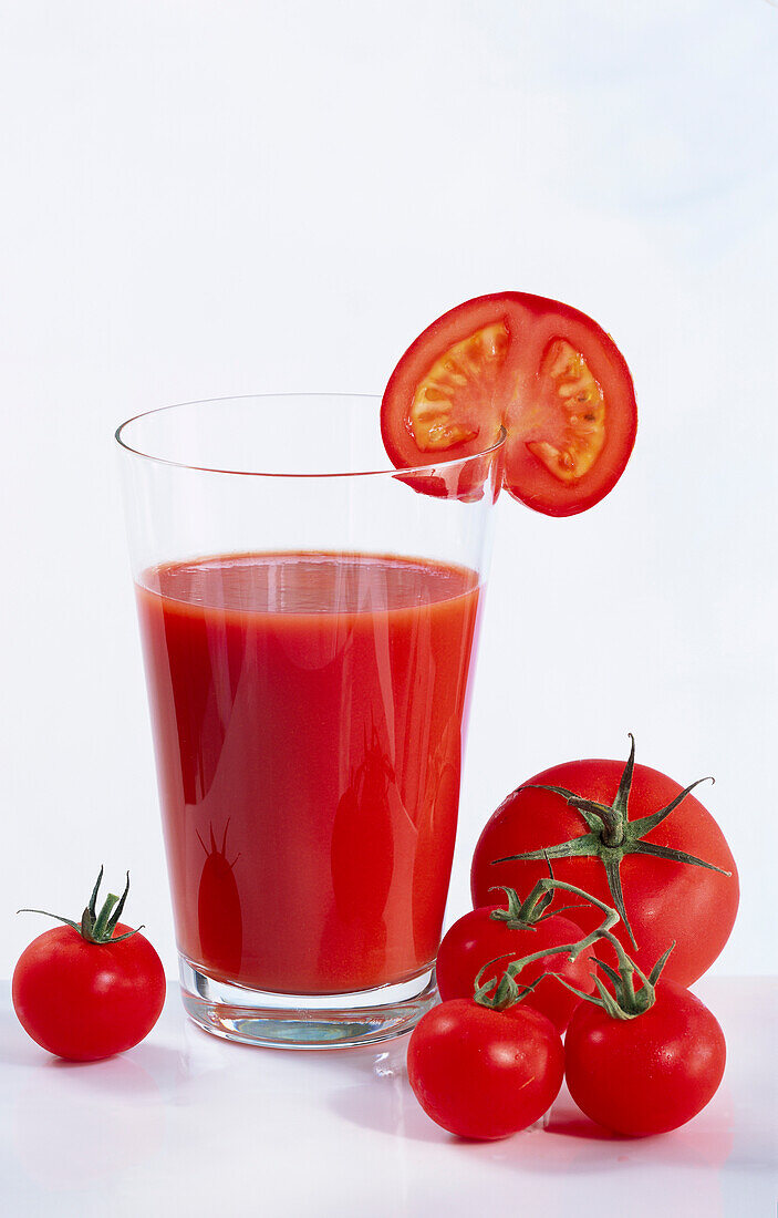 Glas mit Tomatensaft, umgeben von Tomaten