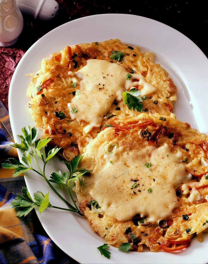 Potato & vegetable rosti with toasted cheese on white platter