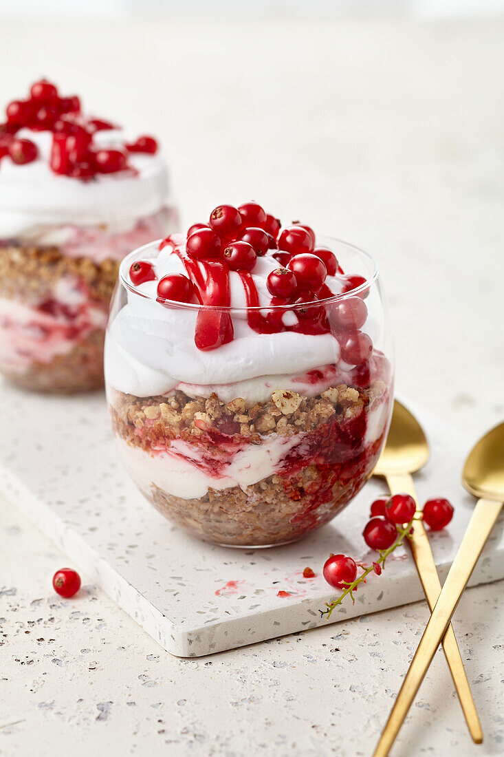 Cake sundaes – layered in a glass: oat and nut cake crumbs, currant cream, whipped cream and a generous sauce drizzle
