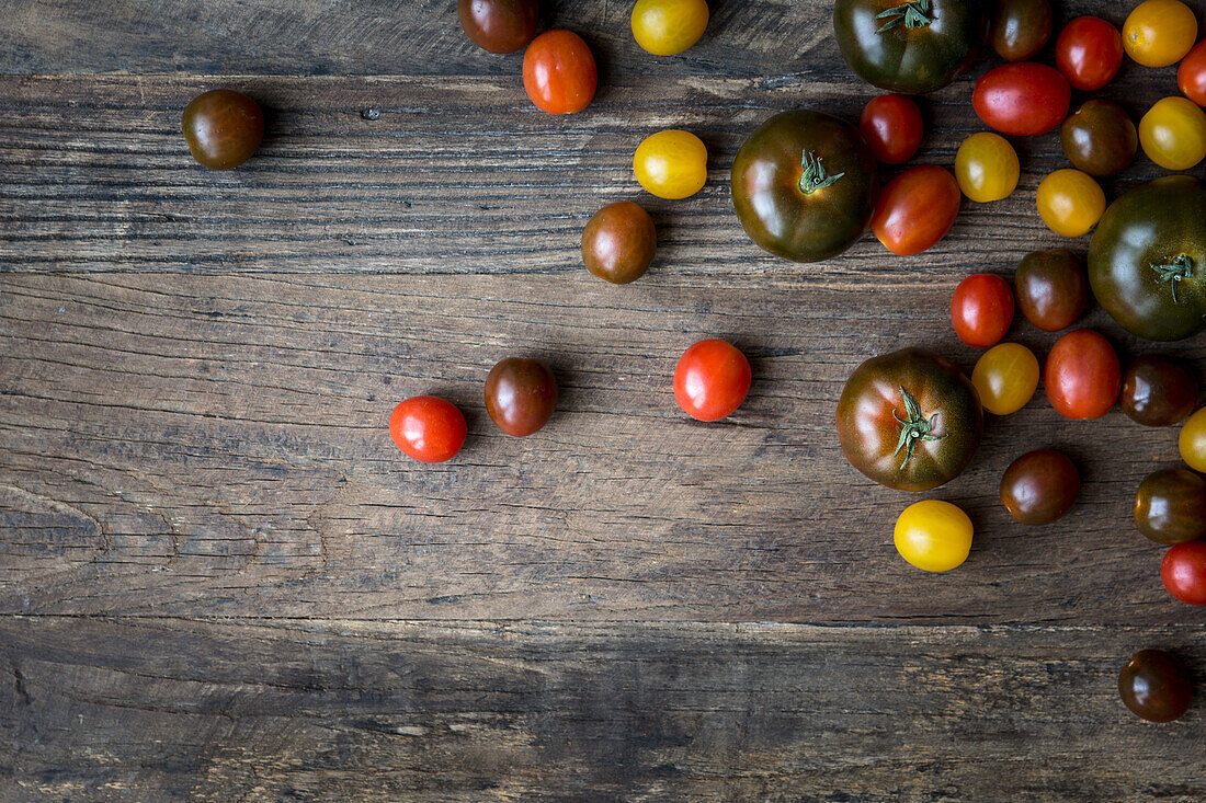Mixed varieties of tomatoes on a wooden surface