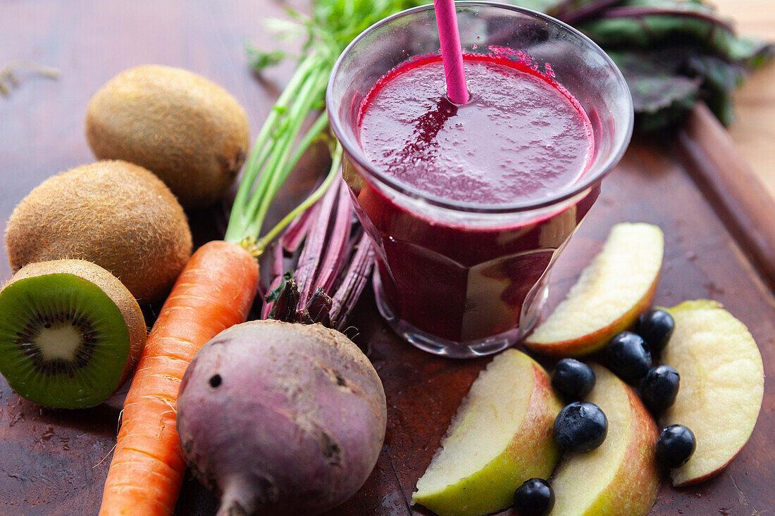 Beet smoothie surrounded by fruit and vegetables
