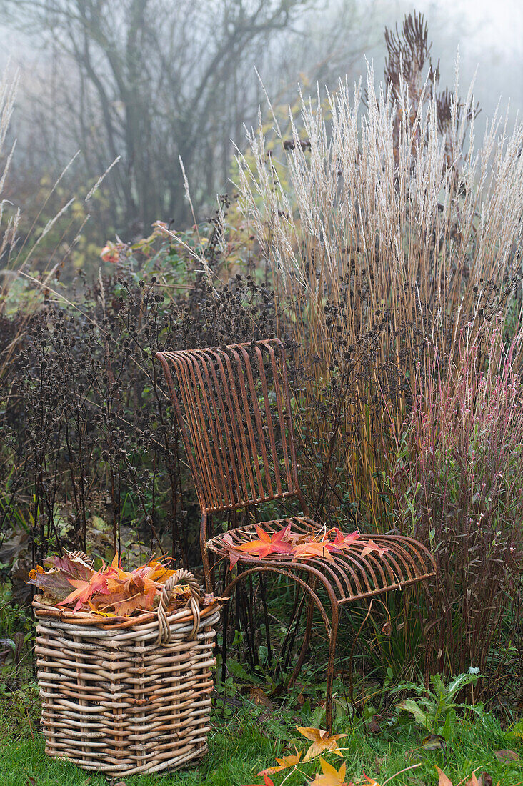 Vintage chair, next to a woven basket with leaves in the late autumn garden
