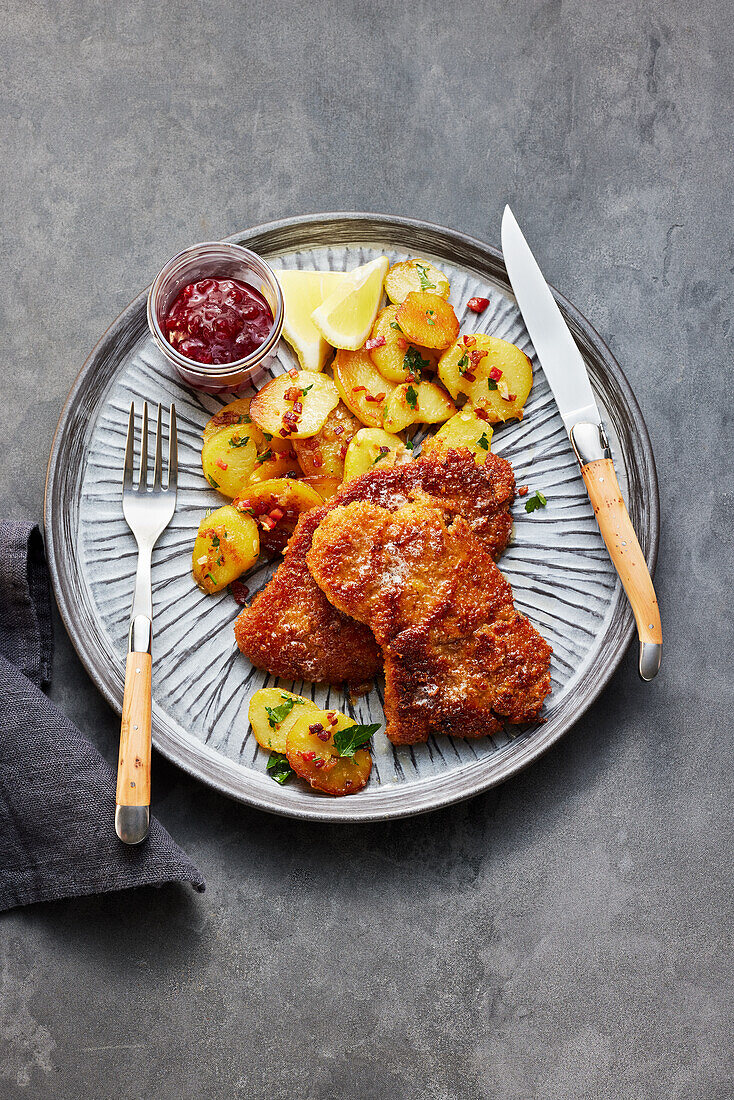 breaded veal cutlet (Wiener Schnitzel) with fried potatoes and cranberries