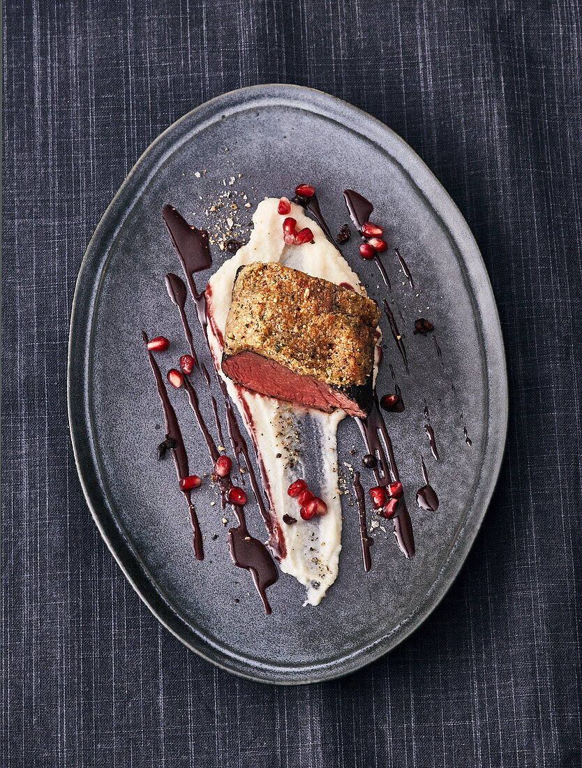 Venison loin in nut crust served on a celery puree and pomegranate sauce