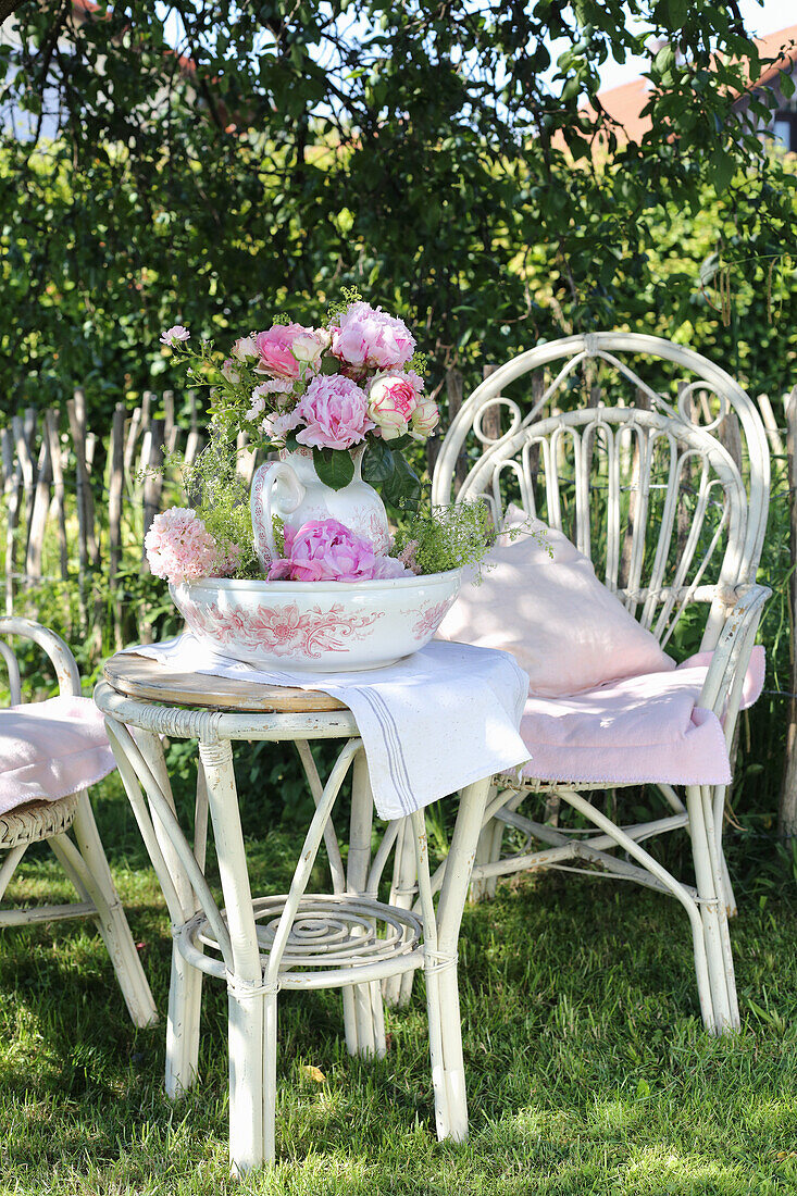 Bouquet of peonies in nostalgic vase on a garden table