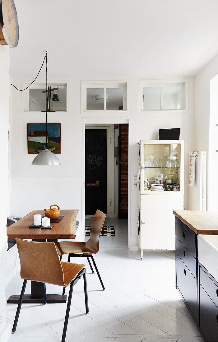 Essbereich mit Holztisch, Holzstühlen und Vintage-Vitrinen-Schrank