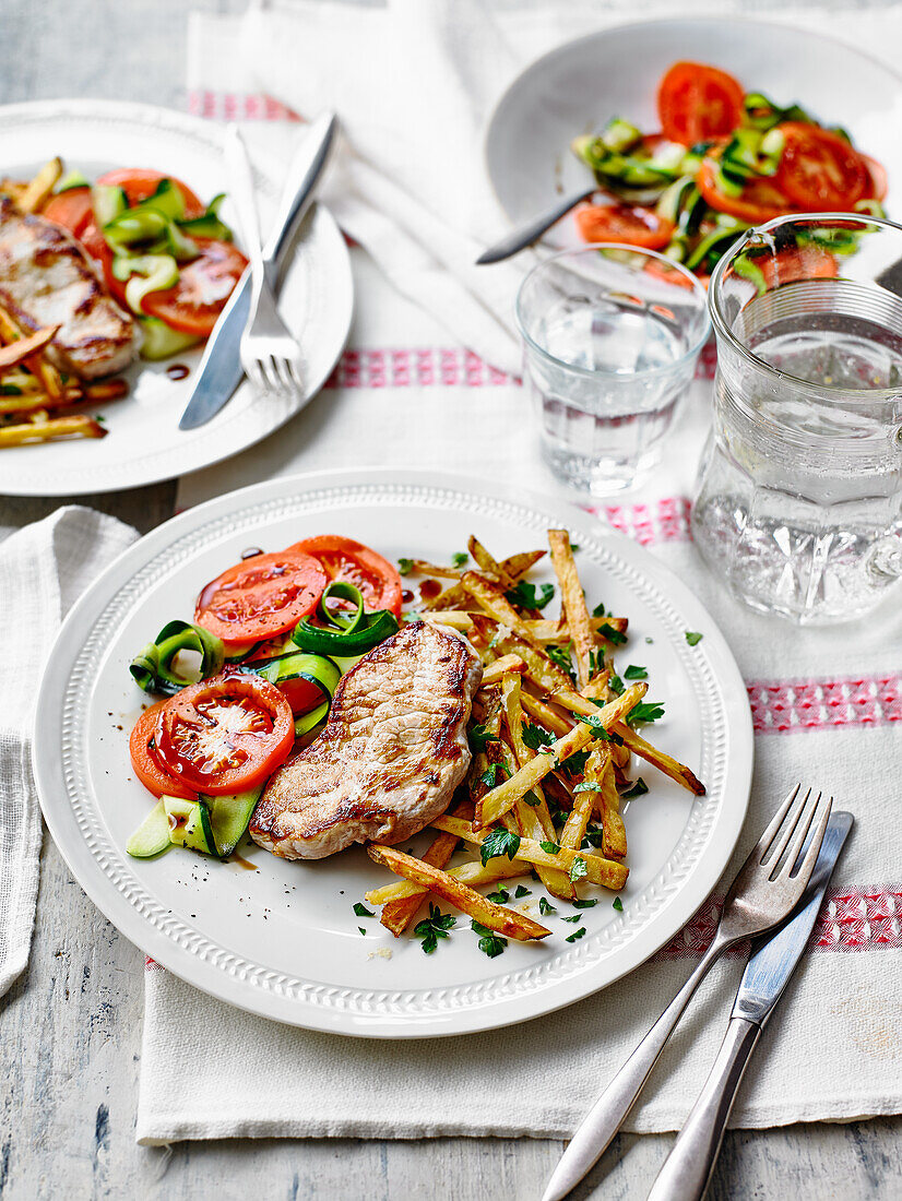 Gebratene Schweinemedaillons mit Pommes und Zucchini-Tomaten-Salat