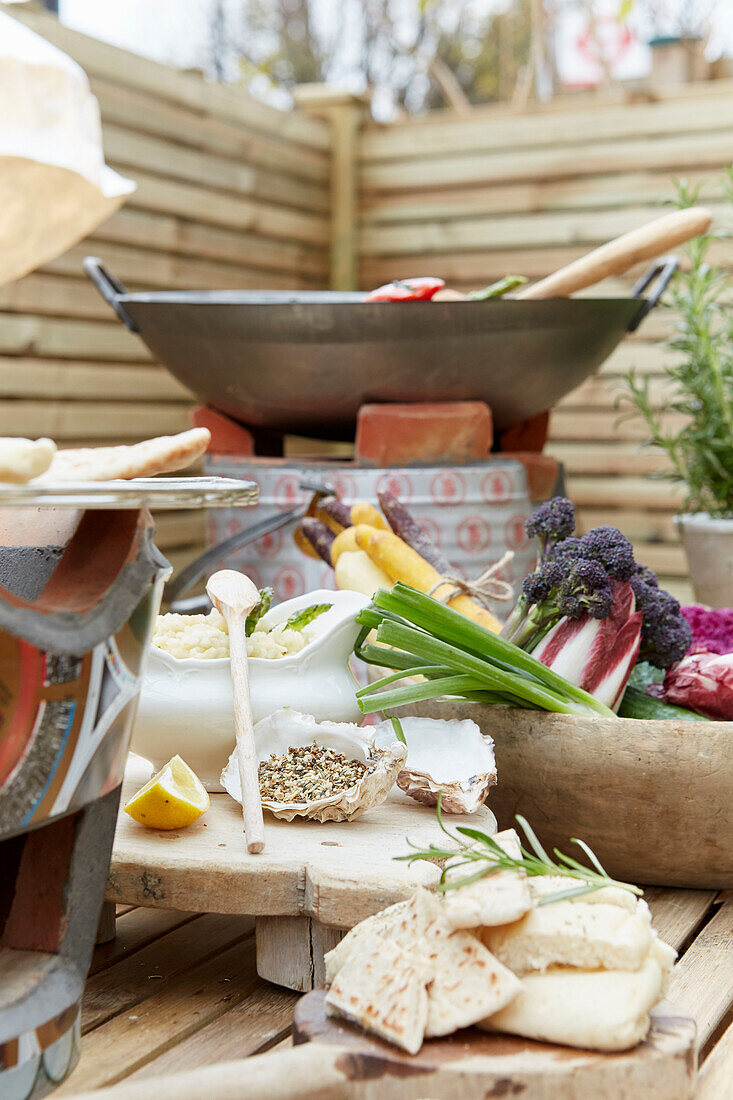 Gartentisch mit frischen Kräutern, Gemüse und Fladenbrot