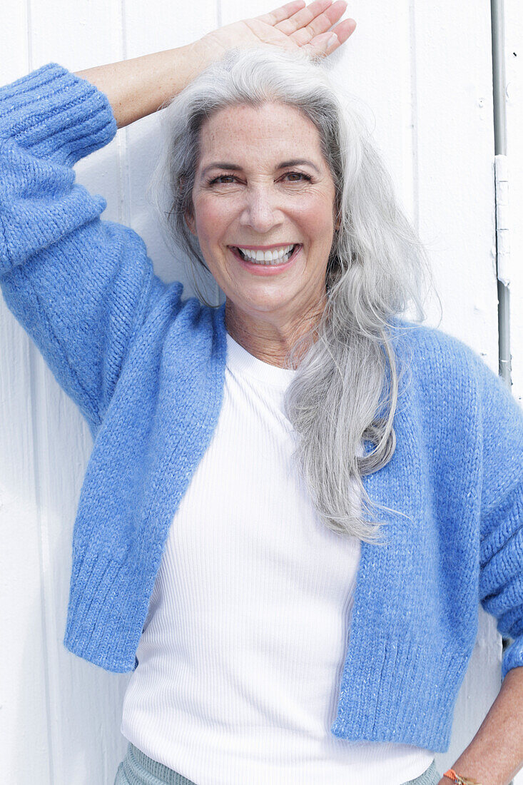 Mature woman with grey hair in white t-shirt and blue cardigan