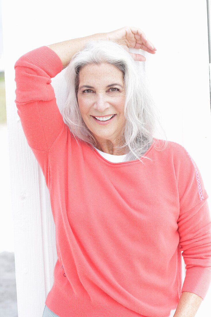 Mature woman with grey hair in salmon jumper