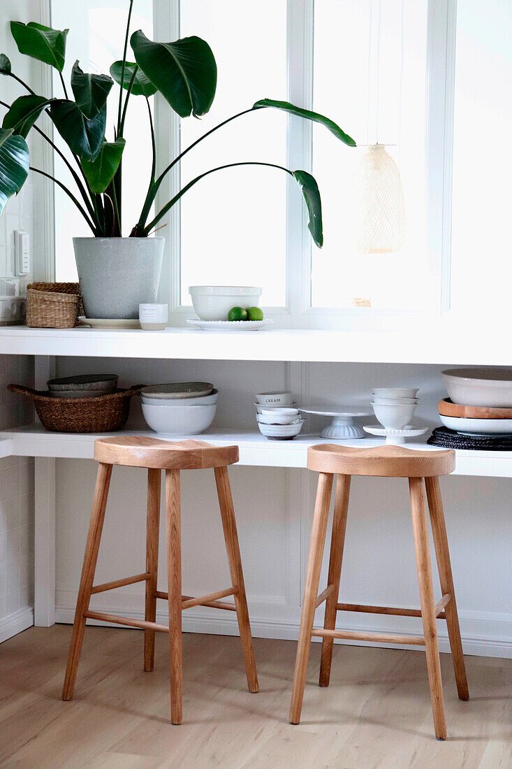 Window sill with wooden bar stools and monstera plant by the window