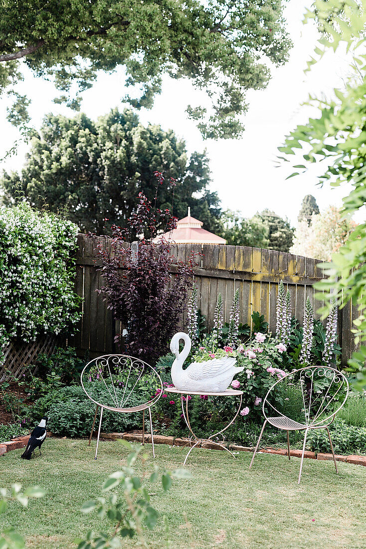 Filigree chairs and table with swan figurine in the garden