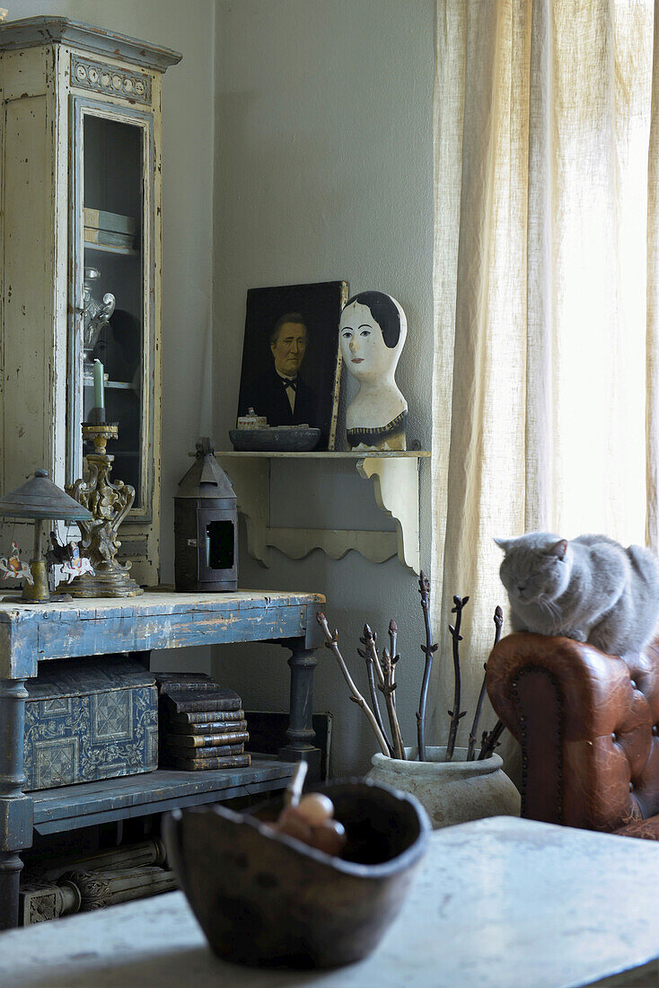 Old wooden shelves below glass-fronted cabinet in shabby-chic interior