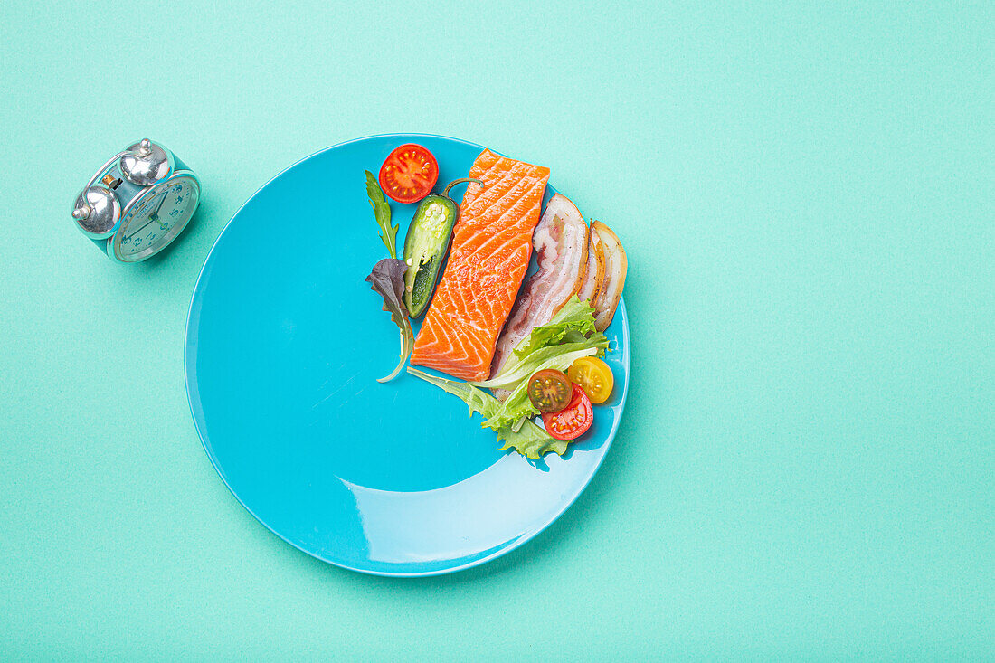 Lachs, Speckscheibe, Gemüse und Salat auf blauem Teller