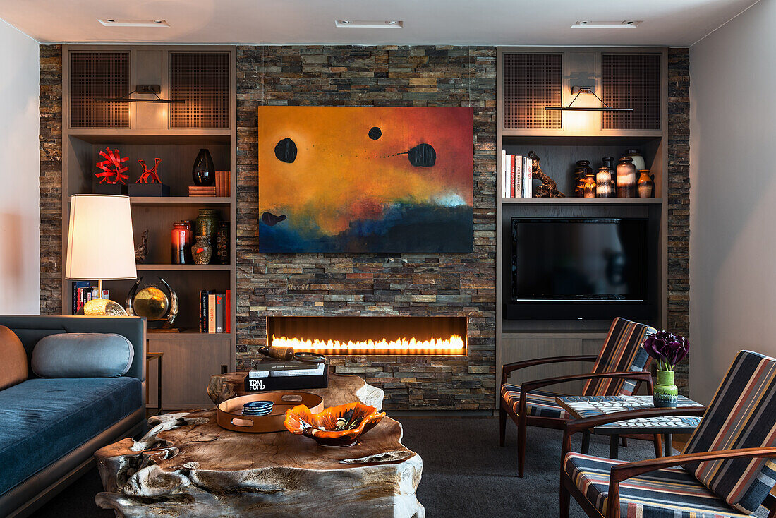 Solid wood coffee table, seating and antique lamps in living room with slate-clad wall