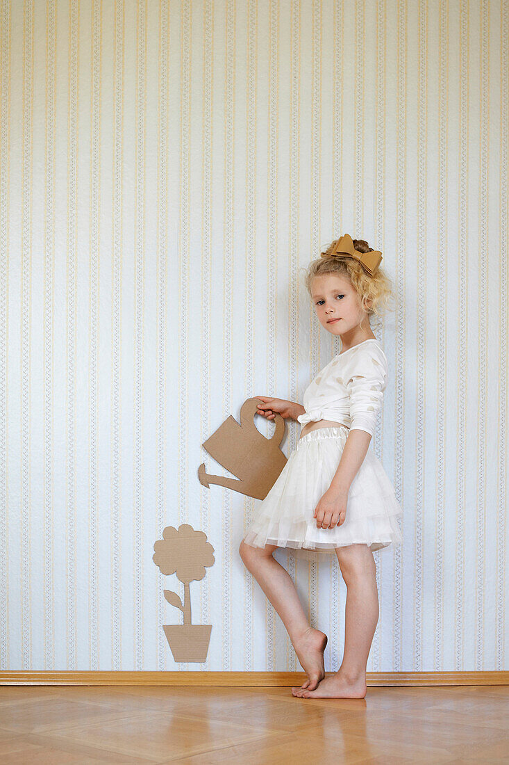 Portrait of girl playing with cardboard watering can and flower