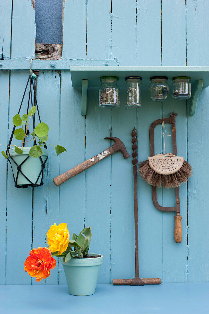 Various tools hanging under DIY shelf with attached jars