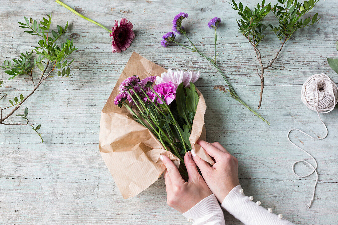 Hände einer Frau, die einen Blumenstrauß einwickelt