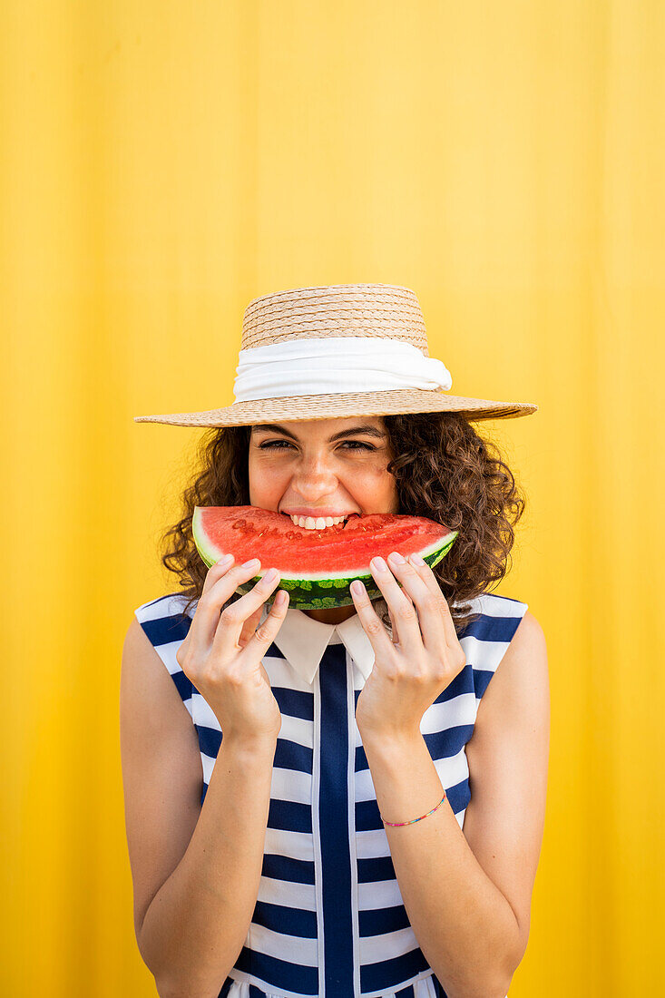Porträt einer Frau, die Wassermelone isst, gelber Hintergrund