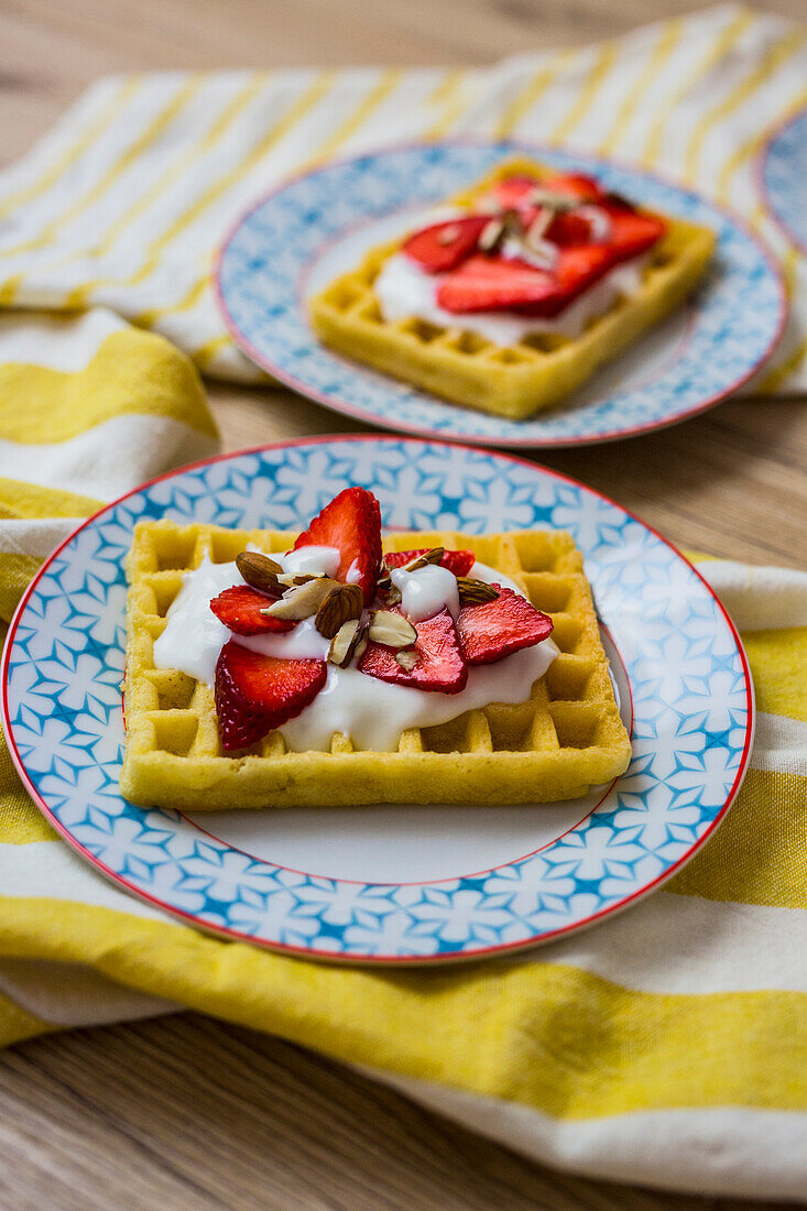 Waffel garniert mit Erdbeeren, griechischem Joghurt und Mandeln auf Teller