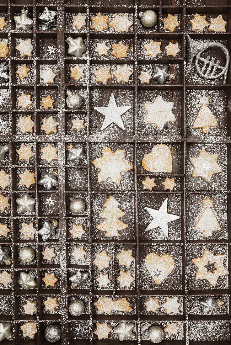 Homemade Christmas cookies, stars and Christmas baubles in old wooden typecase