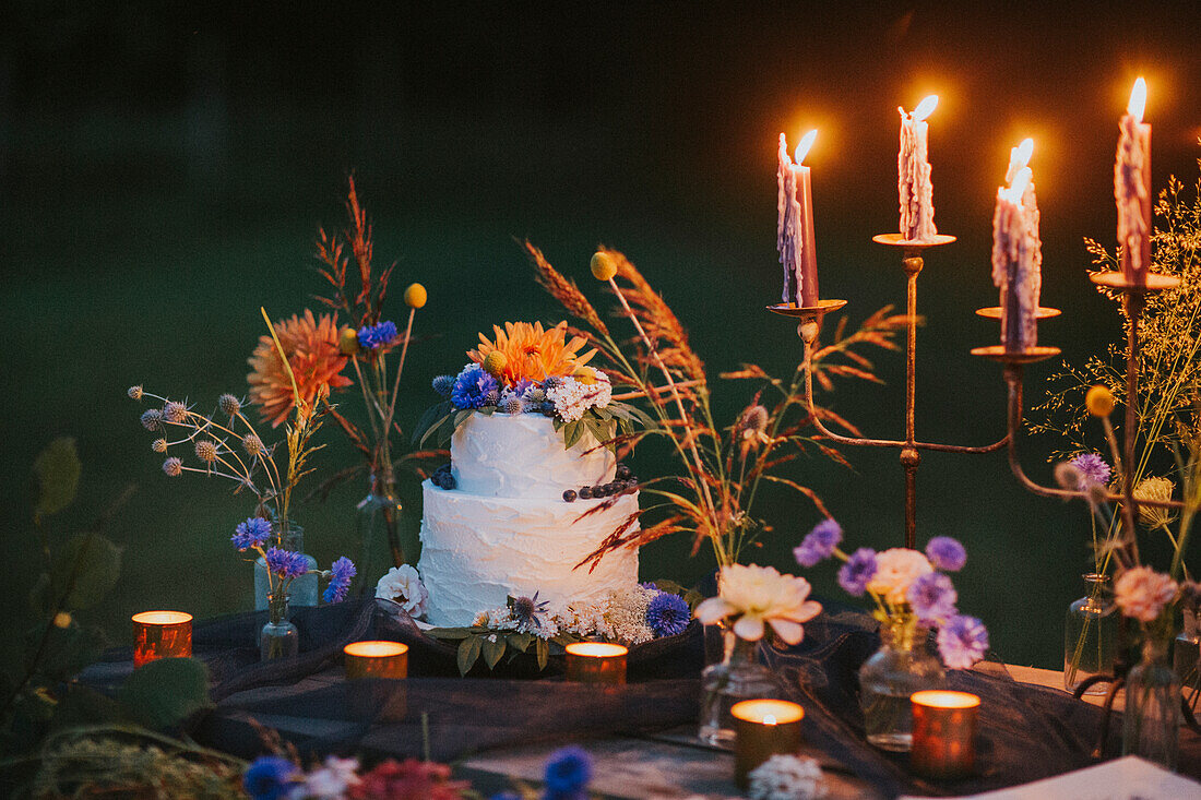 Wedding cake on table with candles outdoors