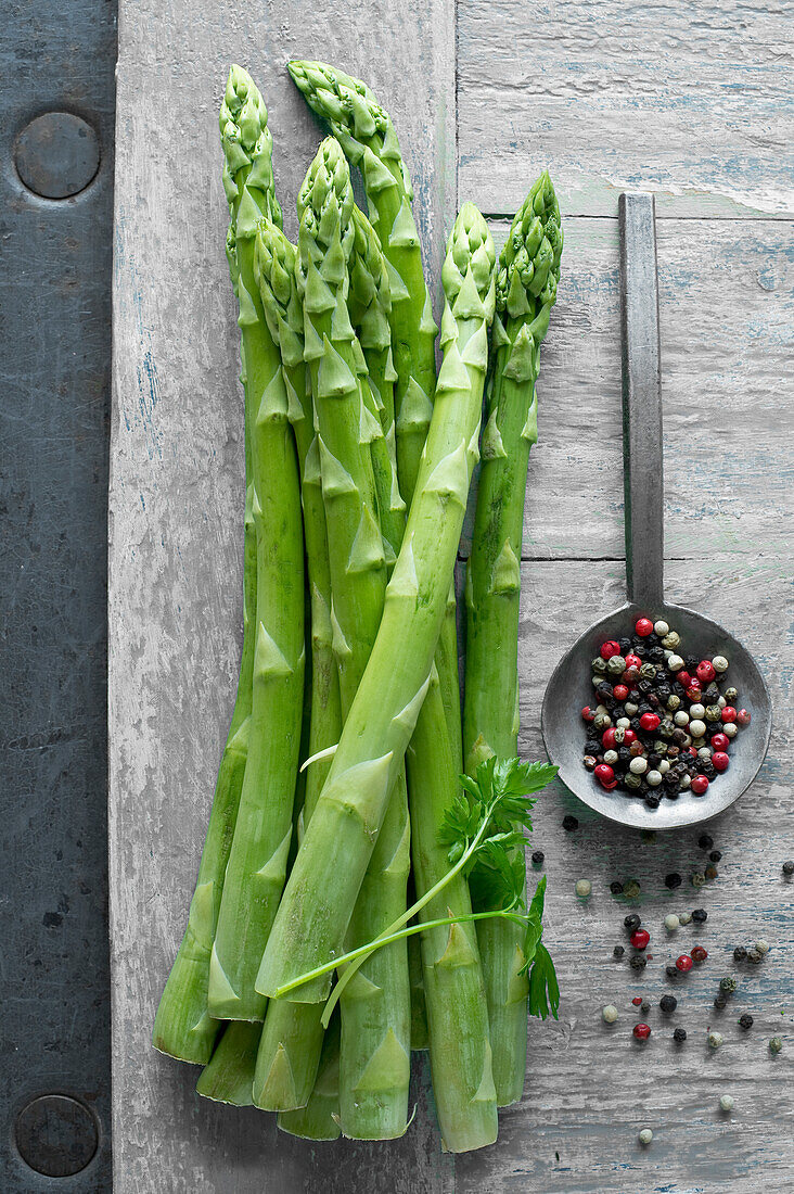 Green asparagus and pepper on wooden table seen from above