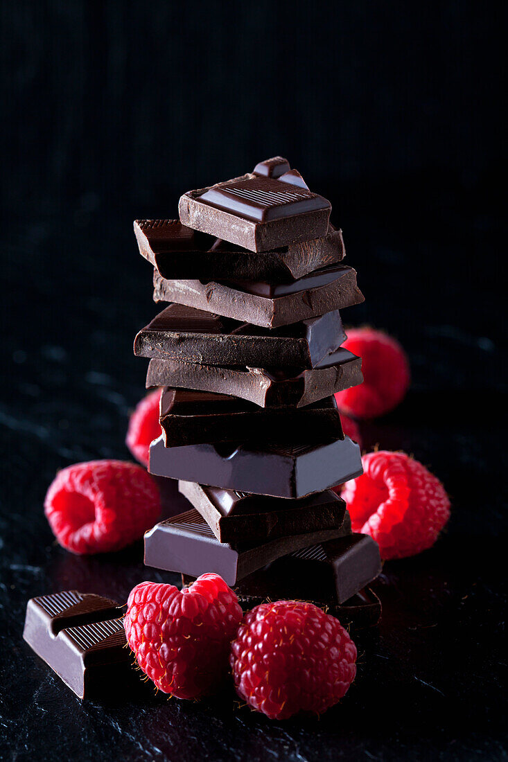 Pile of chocolate pieces and raspberries on black slate