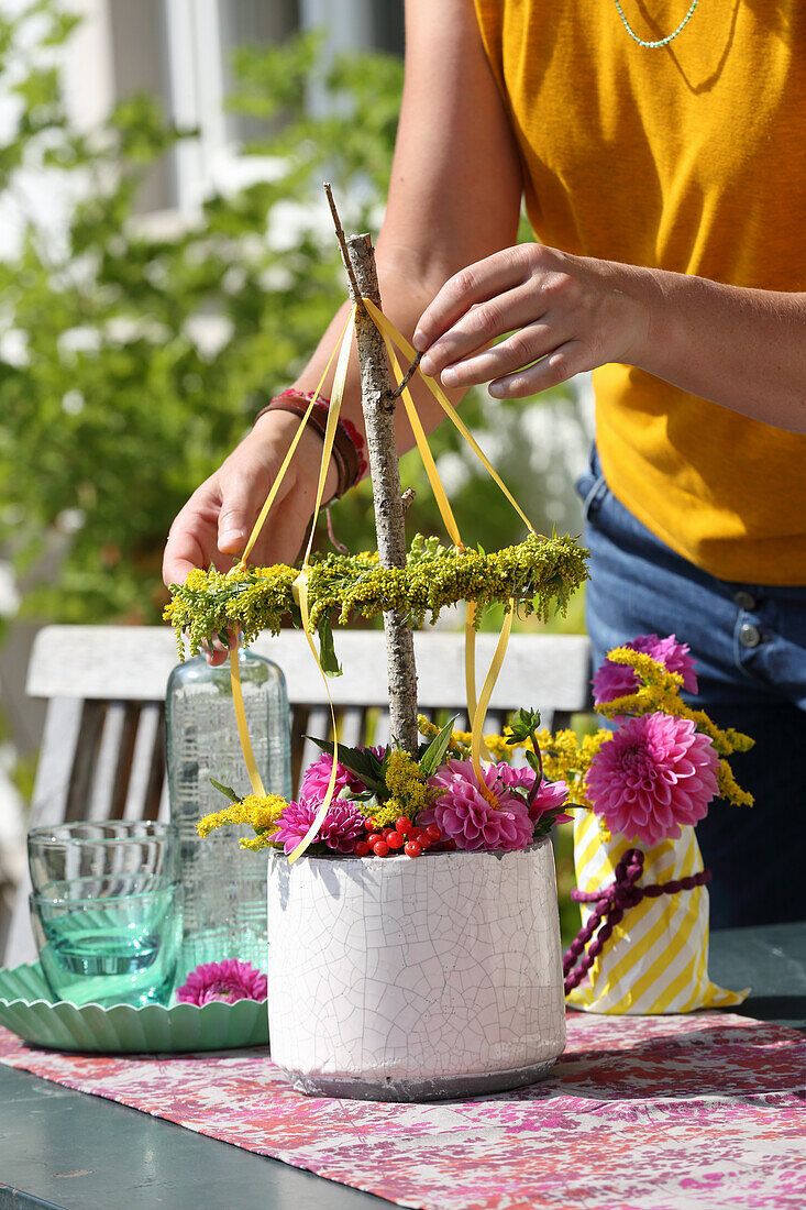 Autumn bouquet of dahlias, goldenrod and red viburnum berries below tiny maypole wreath