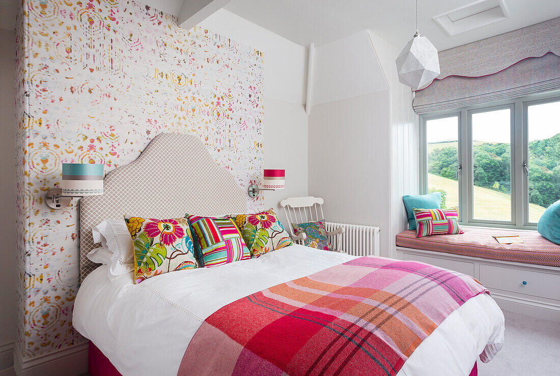 Bedroom with colorful accent wall, decorative throw pillows and window seat