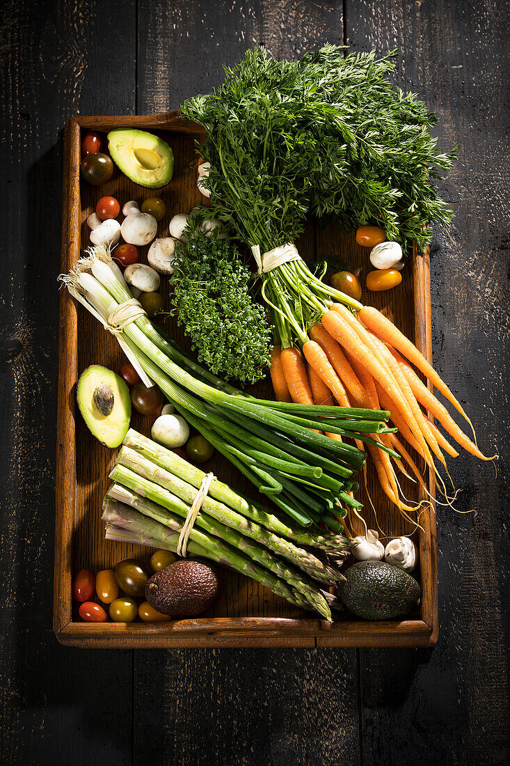 Various organic vegetables on dark wooden tray