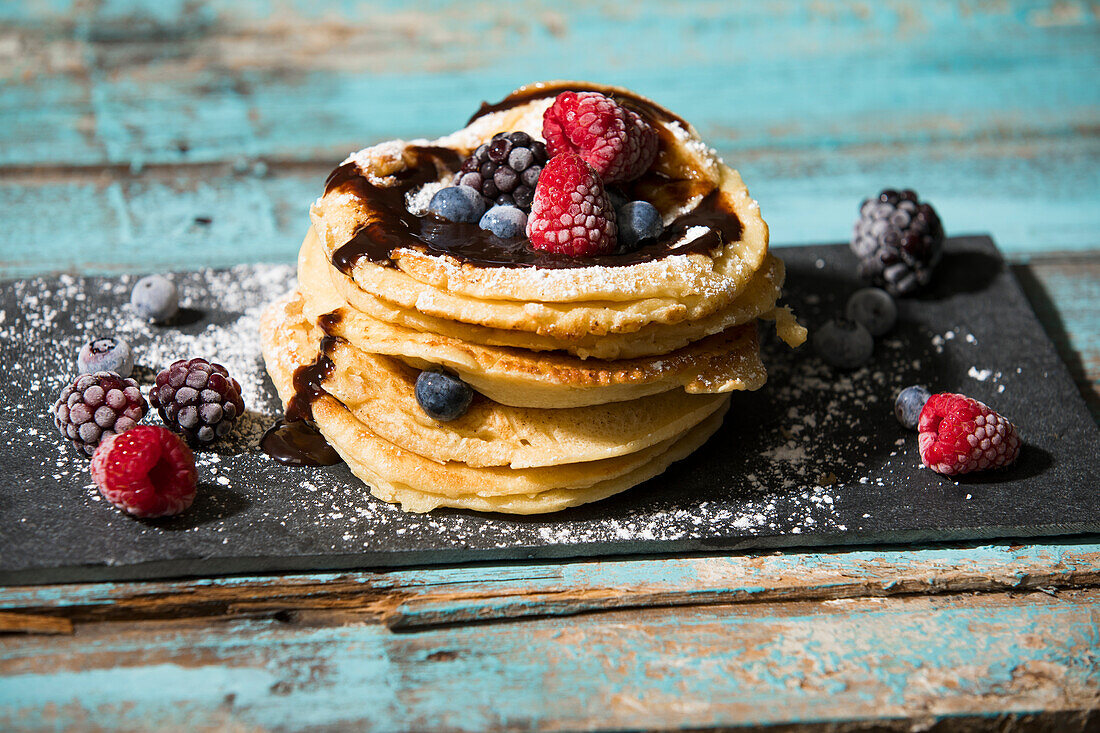 Close-up of pancakes with chocolate sauce and various berries on table