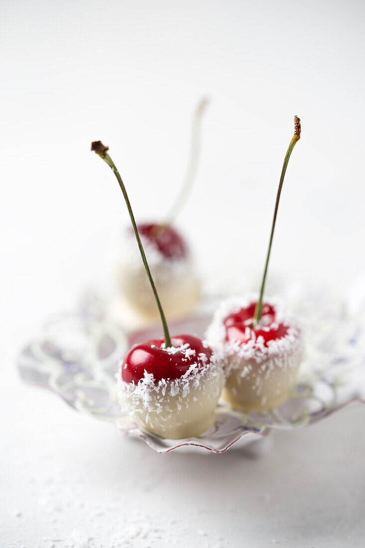 Cherries covered with white chocolate and grated coconut in bowl