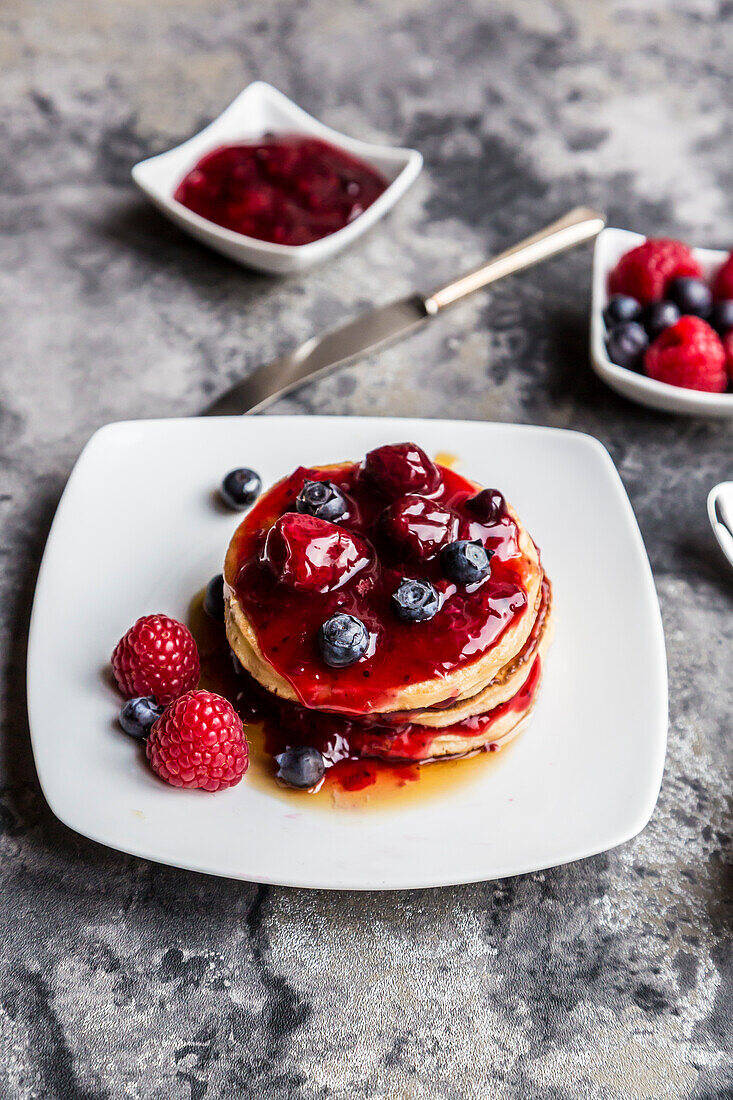 Pancakes with red fruit jelly, maple sirup, raspberry and blueberry